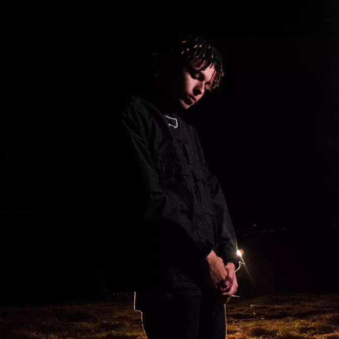 A night portrait of Thalles Leal dressed in black under a focused light.