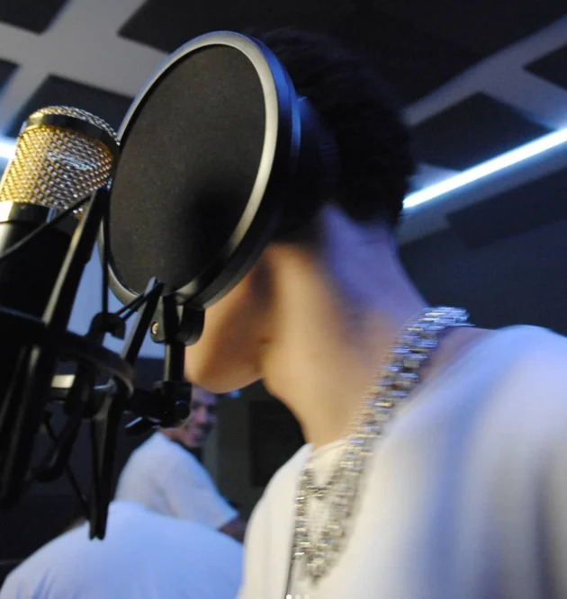 Thalles Leal during a recording session beside a golden microphone and pop filter.